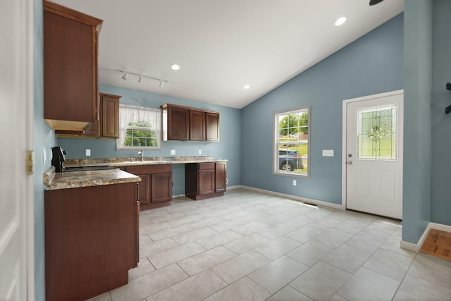 kitchen with stove, light tile patterned floors, plenty of natural light, and lofted ceiling