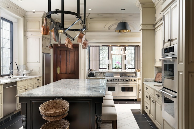 kitchen with cream cabinets, light stone countertops, sink, and stainless steel appliances