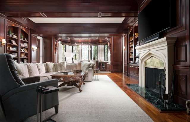 living room with a high end fireplace, wood-type flooring, crown molding, and beam ceiling