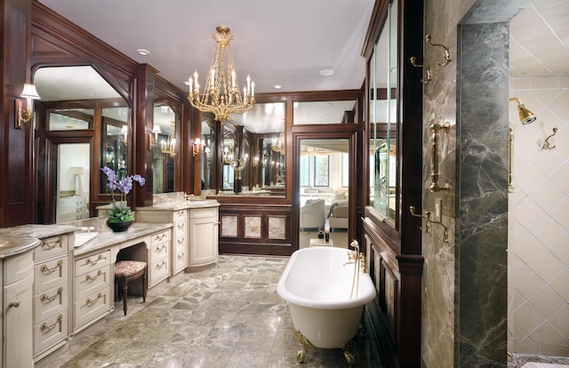 bathroom featuring a notable chandelier, vanity, and a tub to relax in