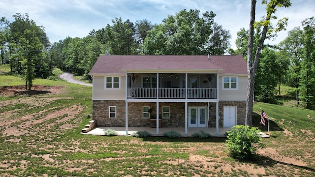 rear view of house with a sunroom, a lawn, french doors, and a patio