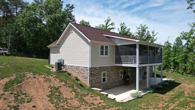 back of property featuring central air condition unit, a patio area, a yard, and a sunroom