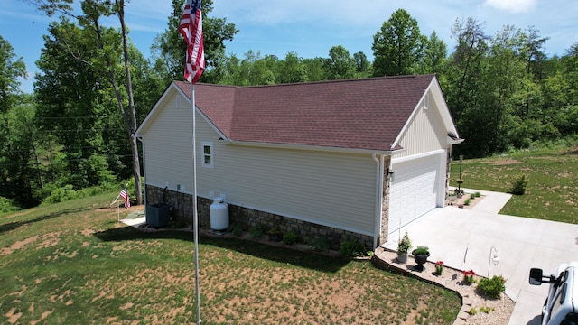 view of side of property with a lawn, central AC, and a garage