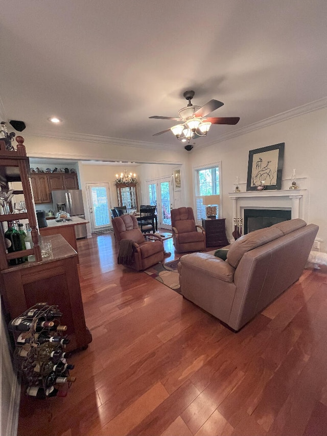 living room featuring wood-type flooring, ceiling fan, and crown molding