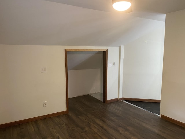 additional living space with baseboards, lofted ceiling, and dark wood-style flooring