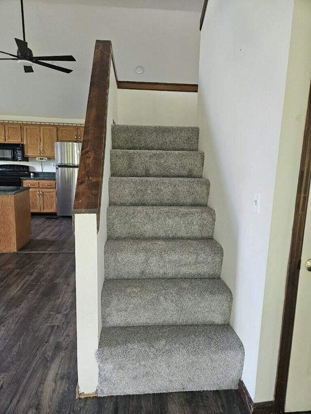 stairs featuring wood finished floors and a ceiling fan