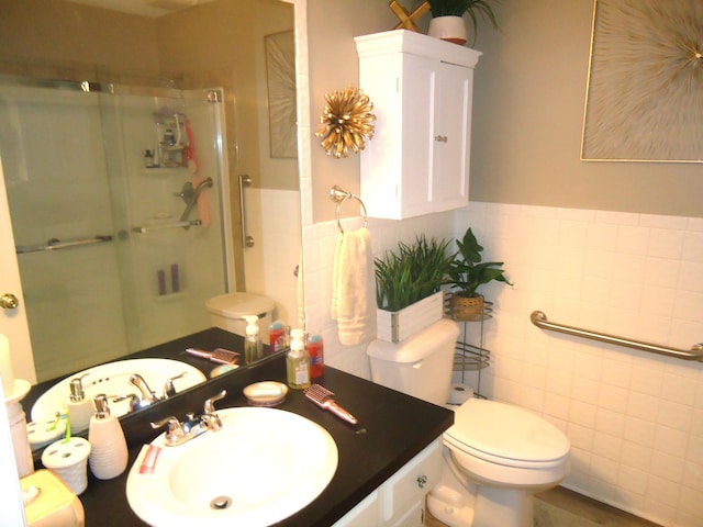 bathroom featuring vanity, toilet, a shower with door, and tile walls