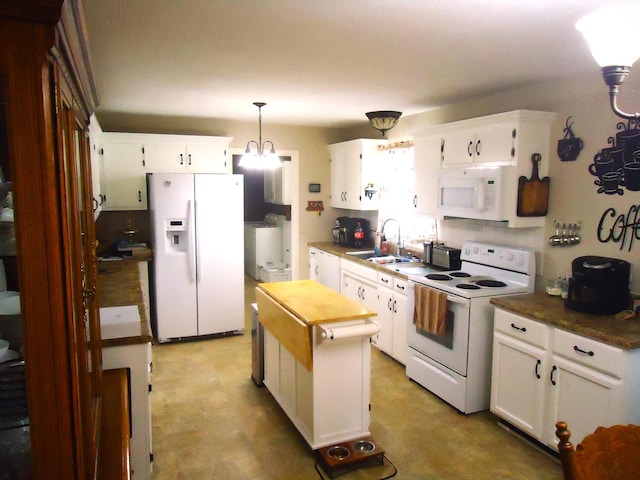 kitchen featuring white appliances, a kitchen island, sink, decorative light fixtures, and white cabinetry