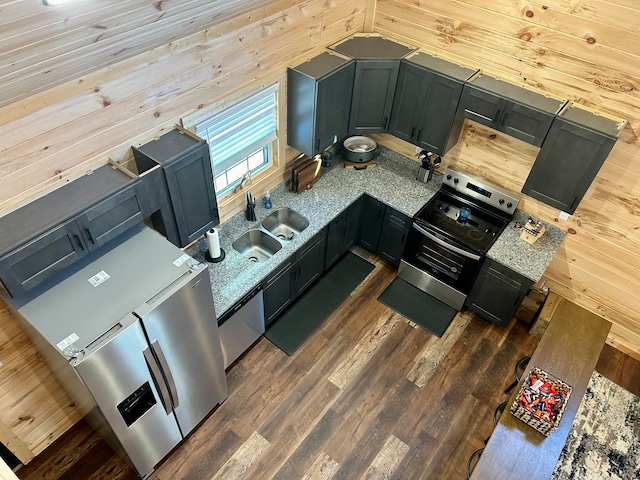 kitchen featuring wooden walls, sink, appliances with stainless steel finishes, light stone counters, and dark hardwood / wood-style flooring