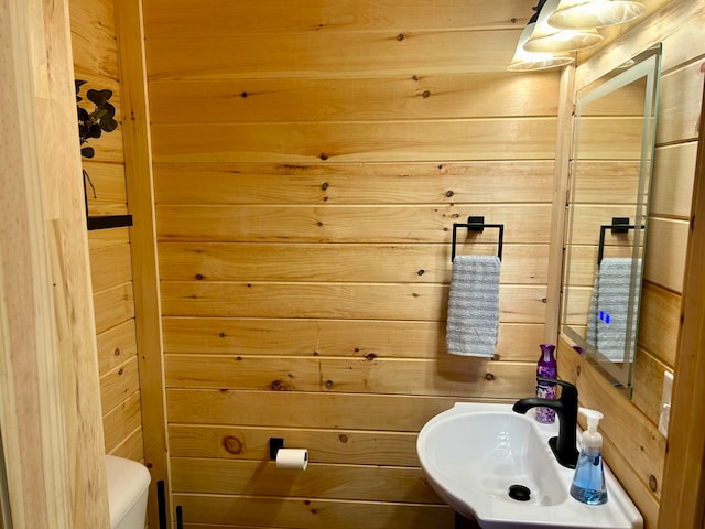 bathroom with sink, wooden walls, and toilet