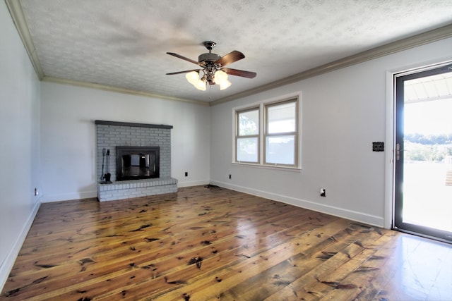 unfurnished living room featuring ceiling fan, a fireplace, dark wood-type flooring, a textured ceiling, and ornamental molding