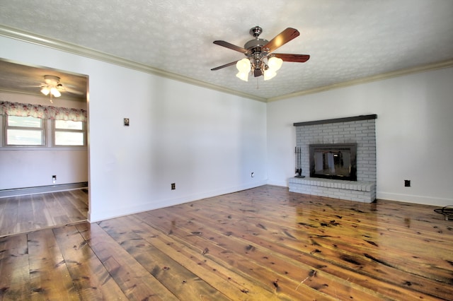 unfurnished living room with hardwood / wood-style floors, ceiling fan, a fireplace, a textured ceiling, and ornamental molding