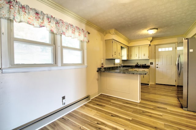 kitchen with kitchen peninsula, stainless steel fridge, a textured ceiling, and light hardwood / wood-style floors