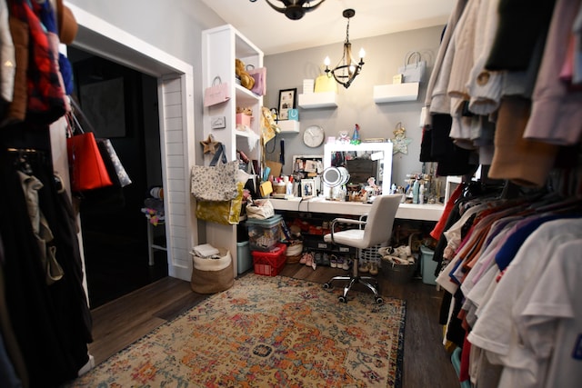 walk in closet with an inviting chandelier and dark hardwood / wood-style flooring