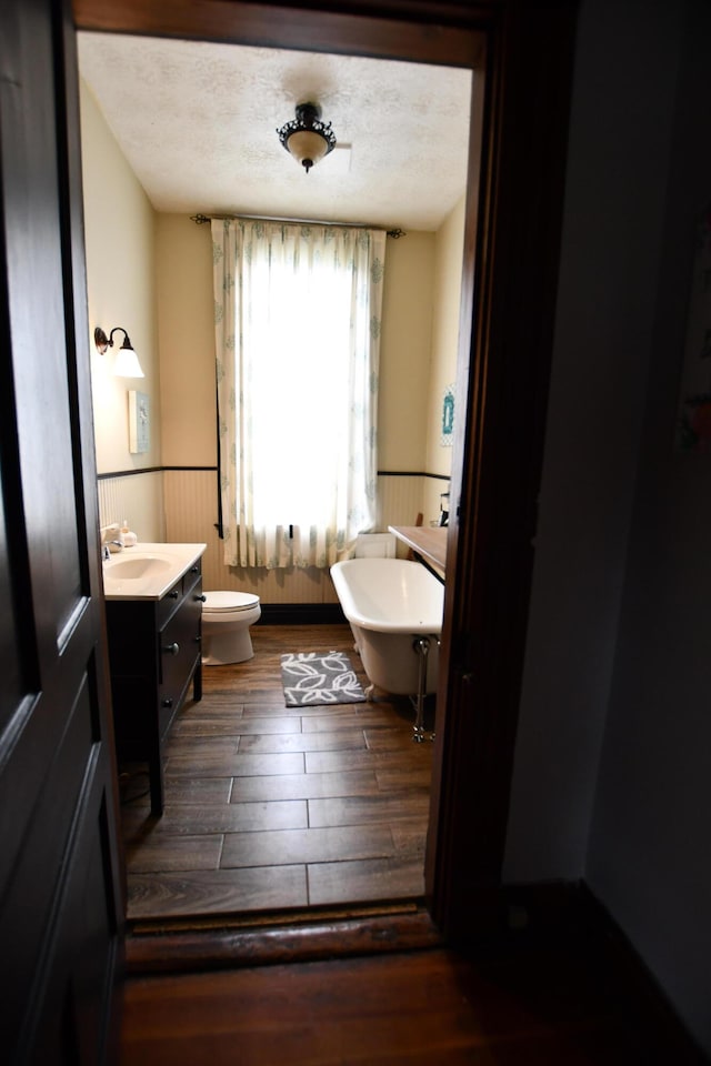 bathroom with a textured ceiling, vanity, toilet, and hardwood / wood-style floors