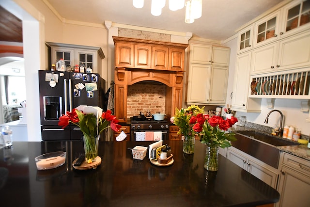 kitchen featuring black fridge with ice dispenser, high end range oven, sink, and crown molding