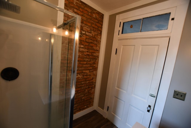 bathroom with brick wall, wood-type flooring, and an enclosed shower