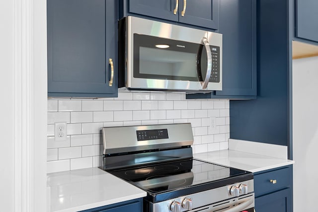 kitchen with blue cabinets, decorative backsplash, and appliances with stainless steel finishes