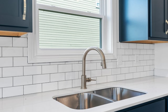 interior details with sink, blue cabinetry, and backsplash