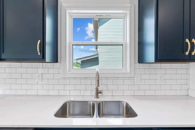 kitchen featuring blue cabinets, decorative backsplash, and sink