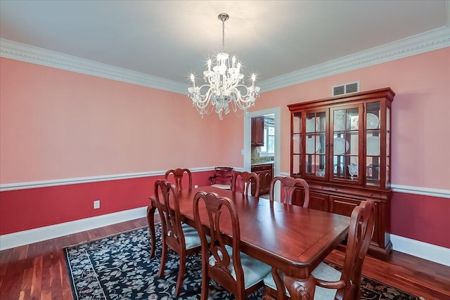 dining space featuring dark hardwood / wood-style flooring, crown molding, and a chandelier