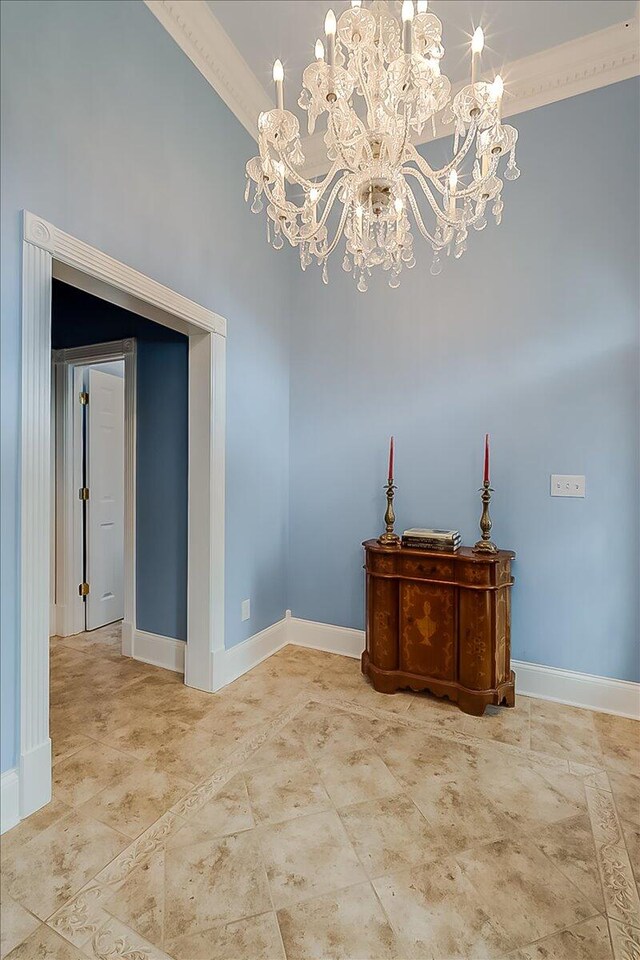 tiled spare room with an inviting chandelier and crown molding