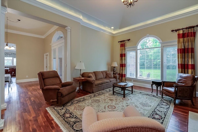 living room featuring a notable chandelier, decorative columns, crown molding, and dark hardwood / wood-style flooring