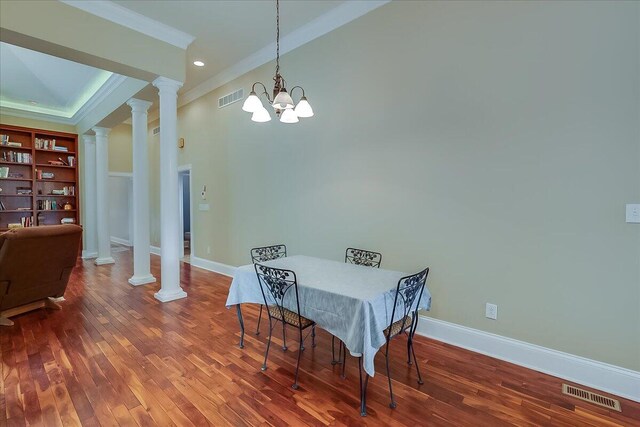 dining area with a notable chandelier, dark hardwood / wood-style flooring, ornamental molding, and decorative columns