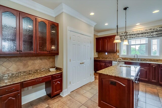 kitchen with decorative light fixtures, tasteful backsplash, a kitchen island with sink, sink, and light tile floors