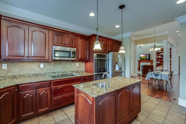 kitchen featuring backsplash, light tile floors, hanging light fixtures, sink, and appliances with stainless steel finishes