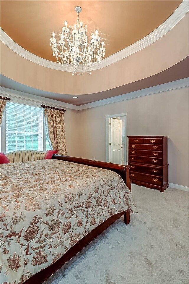 bedroom featuring a tray ceiling, carpet flooring, crown molding, and an inviting chandelier