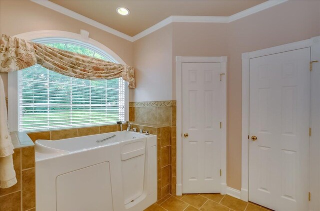 bathroom with tile walls, tile floors, crown molding, and a washtub