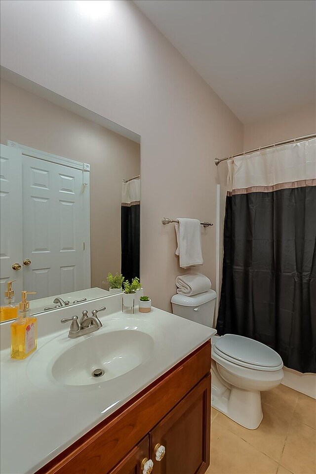 bathroom featuring tile floors, vanity, and toilet