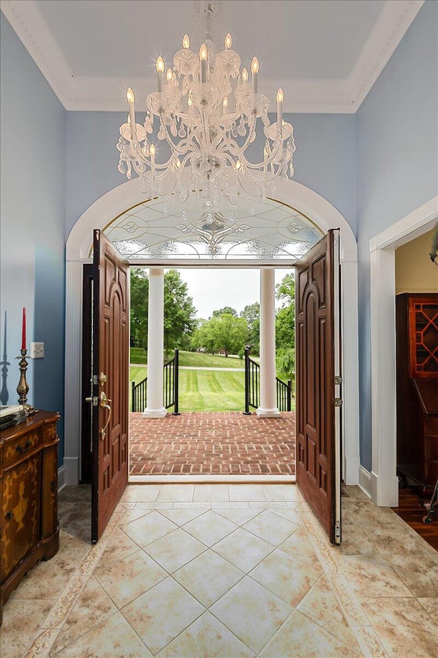 tiled foyer featuring an inviting chandelier and crown molding