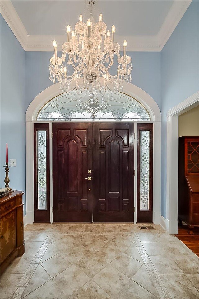 tiled foyer entrance with a notable chandelier and ornamental molding