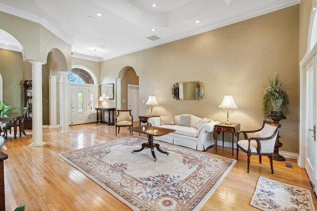 living room featuring light hardwood / wood-style floors, french doors, ornamental molding, a tray ceiling, and a high ceiling