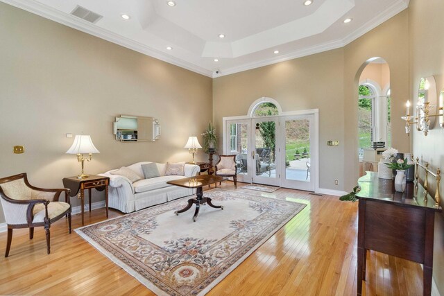 living room featuring a towering ceiling, light hardwood / wood-style floors, and a tray ceiling