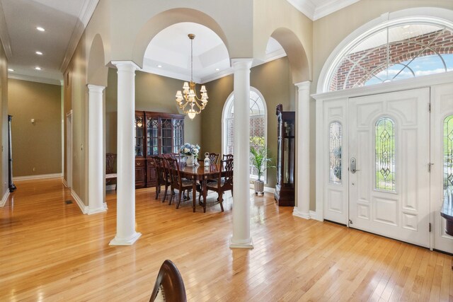 dining area featuring a notable chandelier, a towering ceiling, ornamental molding, and light hardwood / wood-style floors