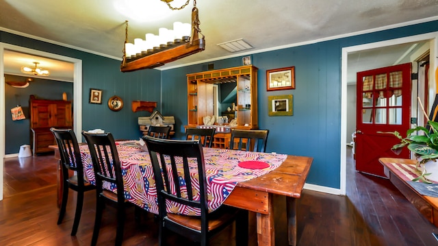 dining room featuring dark wood-type flooring, a notable chandelier, and ornamental molding