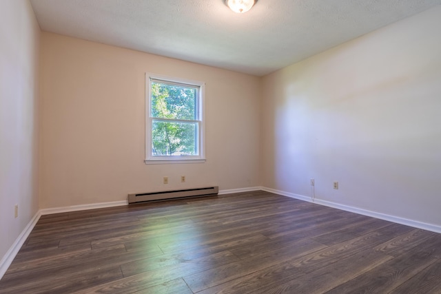 spare room featuring dark hardwood / wood-style floors, a textured ceiling, and a baseboard heating unit