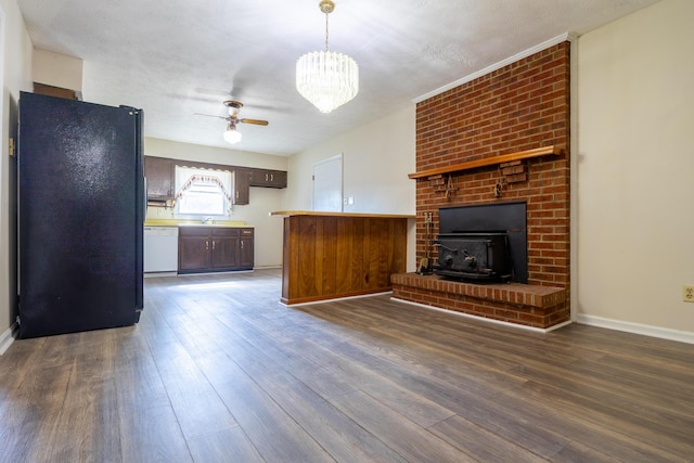 kitchen featuring kitchen peninsula, black fridge, dishwasher, dark hardwood / wood-style floors, and a wood stove