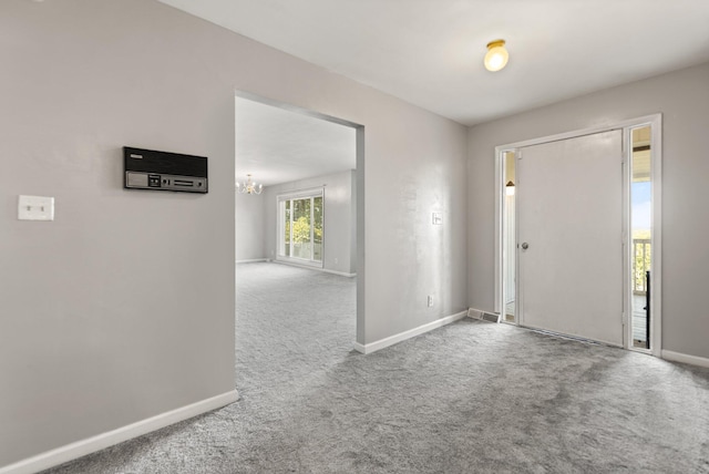 foyer entrance featuring an inviting chandelier and carpet