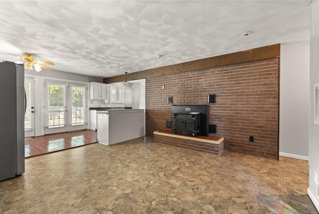 unfurnished living room featuring a wood stove and ceiling fan