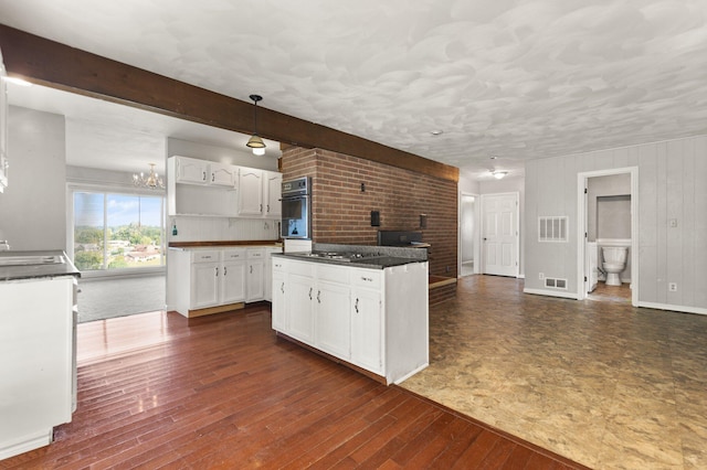 kitchen featuring beam ceiling, white cabinetry, hanging light fixtures, and dark hardwood / wood-style flooring