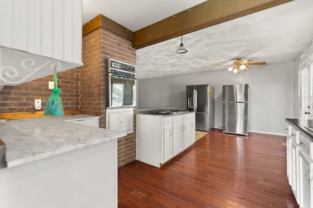 kitchen featuring stainless steel appliances, beam ceiling, ceiling fan, and dark hardwood / wood-style flooring