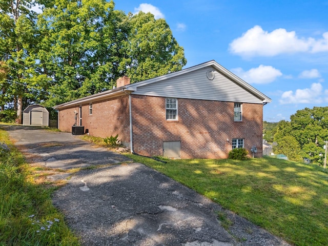 view of property exterior featuring central AC unit, a storage shed, and a yard