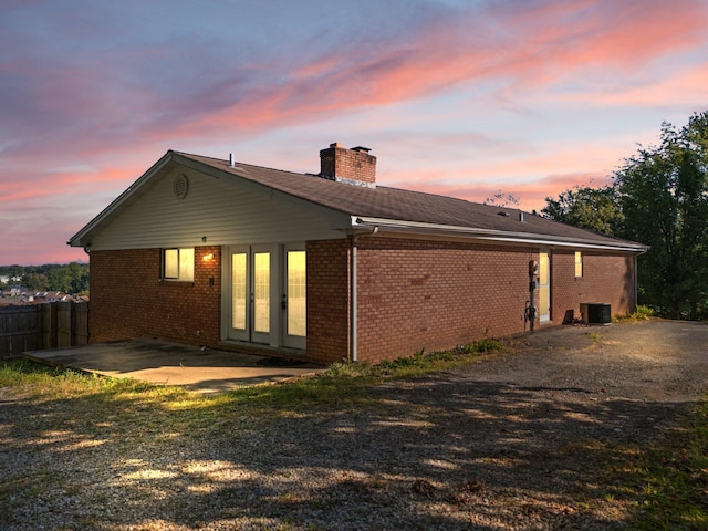 back house at dusk featuring a patio, central AC unit, and french doors