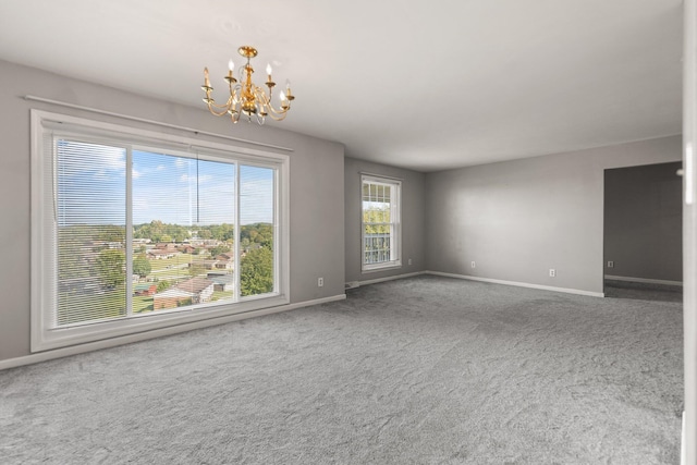 carpeted spare room featuring a notable chandelier