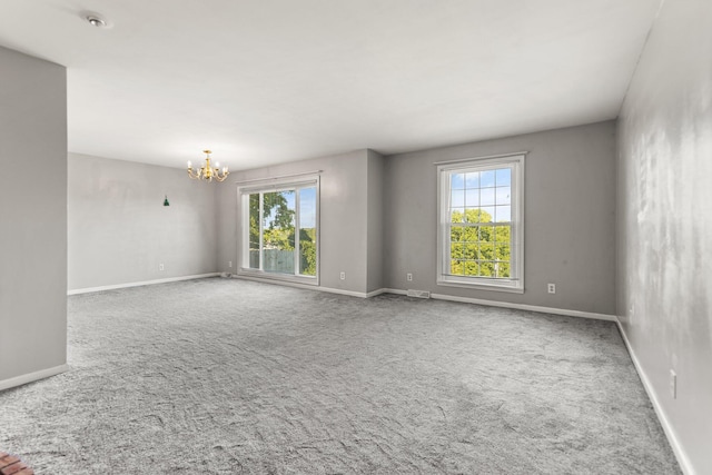 empty room featuring a notable chandelier and carpet