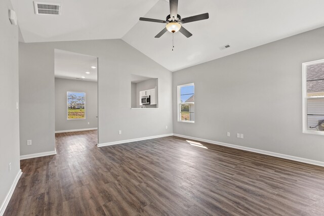 empty room with ceiling fan, a healthy amount of sunlight, lofted ceiling, and dark hardwood / wood-style floors